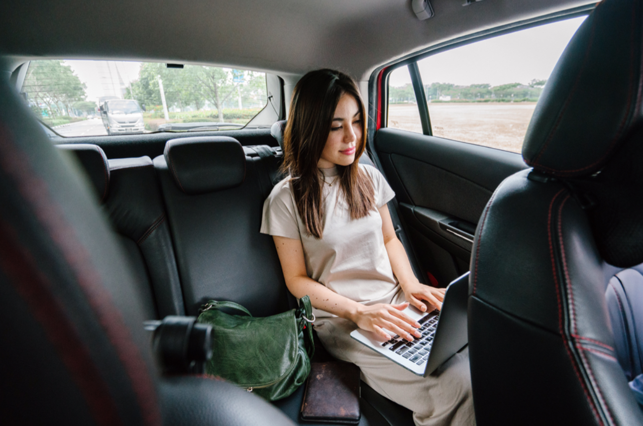 Junge Frau im Taxi am Laptop – Auslagenerstattung
